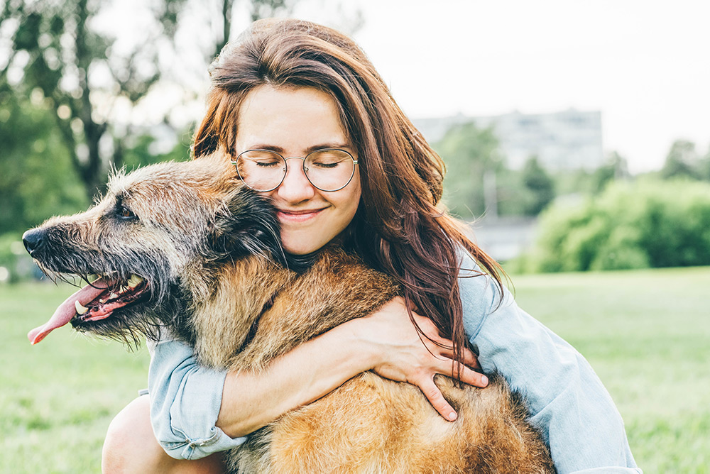 Smiling woman hugging pet dog